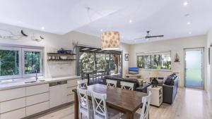 a kitchen and living room with a wooden table and chairs at Coastal Chic Holiday Cottage in Pearl Beach