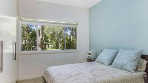 a bedroom with a bed and a window at Coastal Chic Holiday Cottage in Pearl Beach