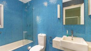 a blue tiled bathroom with a toilet and a sink at Coastal Chic Holiday Cottage in Pearl Beach