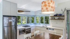 a kitchen with a table and chairs and a refrigerator at Coastal Chic Holiday Cottage in Pearl Beach