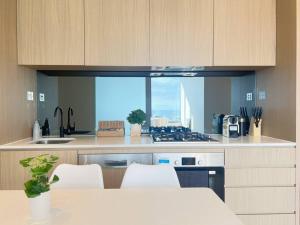 メルボルンにあるStunning 2-Bed Apartment with Panoramic CBD Viewsのシンクとコンロのあるキッチン トップオーブン