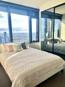 メルボルンにあるStunning 2-Bed Apartment with Panoramic CBD Viewsのベッドが2つと大きな窓がある寝室 +9枚の写真