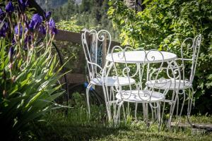 two white chairs and a table in a garden at Lo Verdzé di Torgnon in Torgnon