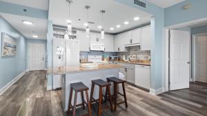 a kitchen with white cabinets and bar stools at Some Beach Some Where at Laketown Wharf #825 by Nautical Properties in Panama City Beach