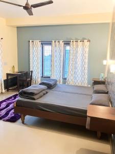 uma cama grande num quarto com duas janelas em Hobo Hostel em Dharamshala