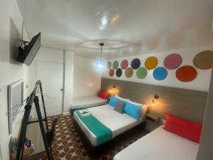 a bedroom with a bed with colorful pillows and a camera at Hotel Tamaiti in Ríohacha