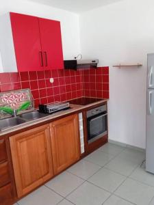 a kitchen with red cabinets and a sink and a refrigerator at Dous'Inn Kreyol Appartement in Grand-Bourg