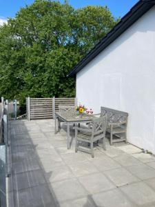 a patio with two benches and a table with flowers at Ferienwohnung Heeser Birkenhof - Urlaub auf dem Bauernhof mit Blick ins Grüne in Weeze