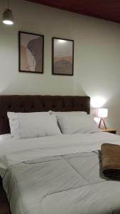 uma grande cama branca com três fotografias na parede em Casa Duplex em Pedra Azul em Domingos Martins