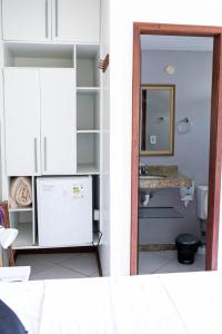 Habitación con baño con lavabo y nevera. en Pousada Estalagem dos Corais da Prainha, en Arraial do Cabo