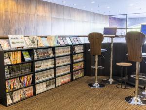 una biblioteca con estanterías de DVD y sillas en Hotel Wing International Nagoya en Nagoya