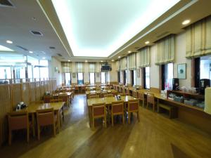 a restaurant with wooden tables and chairs and windows at Hotel Route-Inn Sapporo Kitayojo in Sapporo