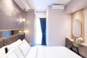 1 dormitorio con cama blanca y espejo en Amalea at Benson Pakuwon Mall, en Surabaya