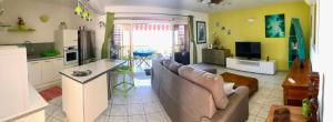 sala de estar con sofá y cocina en Superbe bord de mer, accès lagon et piscine privée, en Paea