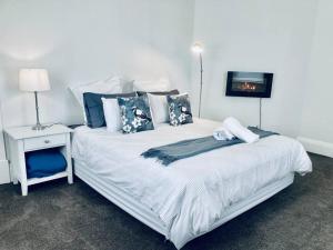 una camera da letto con un grande letto bianco con cuscini blu di Pretty in Penola Sleep 3, a Penola