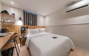 a bedroom with a large white bed and a desk at Just Stay Hotel in Seoul