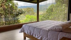 a bedroom with a bed and a large window at Terrabambu Lodge in Mindo
