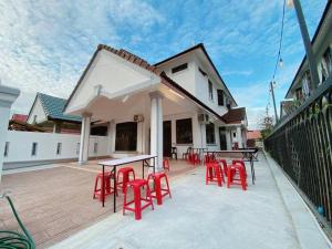 a group of red chairs and tables on a patio at C01 Budget Homestay in Tmn Rinting in Masai