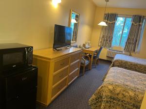 ein Hotelzimmer mit einem TV auf einer Kommode mit einem Schreibtisch in der Unterkunft Fairview Inn in Simcoe