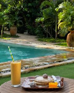 a drink and a plate of food next to a pool at Tropical Temple Siargao Resort in General Luna