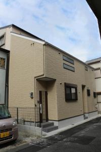 une maison en briques avec une voiture garée devant elle dans l'établissement HANASTAY花渓居 · 梨（NASHI), à Osaka