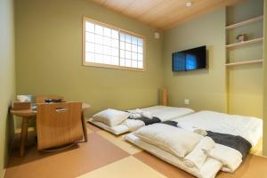 1 dormitorio con 2 camas, mesa y ventana en HANASTAY花渓居 · 梨（NASHI), en Osaka