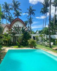 a pool in front of a house with palm trees at Tropical Temple Siargao Resort in General Luna