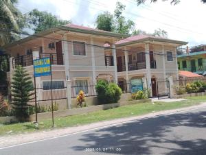 a house with a sign in front of it at Rising Sun Pension House in Oslob