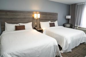 two beds in a hotel room with white sheets at Hôtel Énergie Shawinigan in Shawinigan