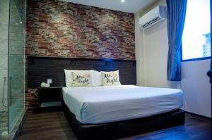 a bedroom with a bed and a brick wall at Apple Hotel Penang in George Town