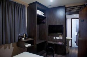 a hotel room with a bed and a desk and a television at Apple Hotel Penang in George Town