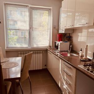 a kitchen with white cabinets and a table and a microwave at Sweet Apartament in Baia Mare