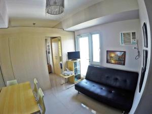 a living room with a black couch and a table at Chill Staycation at Grass Residences in Manila