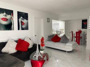 sala de estar con sofá negro y almohadas rojas en Beautiful House 7 min from Miami Airport w FREE parking en Miami
