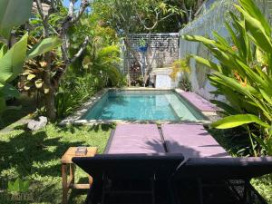 a swimming pool in a yard with a table and chairs at The Jungle House in Canggu