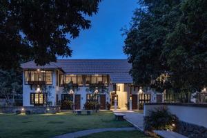 Une grande maison blanche avec des lumières dans la cour dans l'établissement Palin Family Cottage, à Chiang Rai