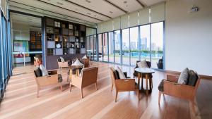 a lobby with tables and chairs and a large window at Citiresort @sea sriracha in Si Racha