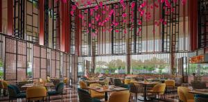 峇六拜的住宿－槟城国际会展中心阿玛瑞酒店，一间带桌椅和粉红色鲜花的餐厅