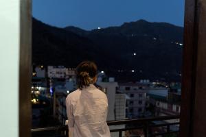 a woman standing on a balcony looking out at the city at Spontrail Hostel in Rishīkesh +58 photos