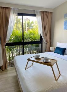 a bedroom with two beds and a table in front of a window at Diamond Resort by I Am Home in Bang Tao Beach