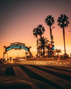 a street with palm trees and a sign at sunset at Casa Playa - Modern, Stylish, Spacious, Gated Entry, Rooftop Pool - BEST LOCATION - 4 BLKS to Ocean Avenue in Los Angeles