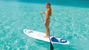 a young girl standing on a paddle board in the water at Casa Playa - Modern, Stylish, Spacious, Gated Entry, Rooftop Pool - BEST LOCATION - 4 BLKS to Ocean Avenue in Los Angeles