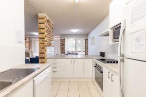 a kitchen with white cabinets and a sink at Bay Parklands 23 located at Little Beach with air con pool and tennis court in Shoal Bay