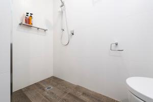 a white bathroom with a shower and a toilet at Gunsynd Studio Apartment in Scone