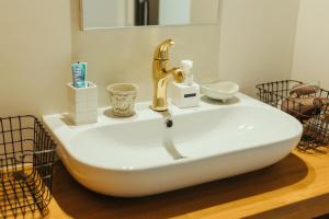 een wastafel met een gouden kraan erop bij 1日2組限定オーシャンビューのお宿-MANANI House- in Ōura