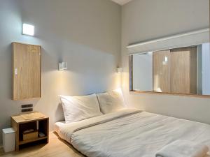 una camera da letto con un letto bianco e una finestra di KW2 Hostel a Kaohsiung