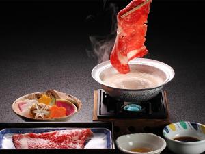 un trozo de comida siendo sumergido en un tazón de comida en Hakone Yunohana Prince Hotel, en Hakone