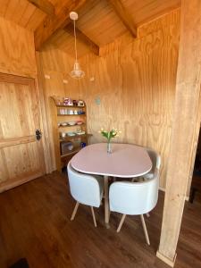 a dining room with a pink table and white chairs at Lomas de Riñihue para 2p in Valdivia