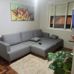 a living room with a gray couch and a window at Amplo apt próximo ao Consulado in Porto Alegre