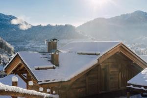 ein schneebedecktes Haus mit Bergen im Hintergrund in der Unterkunft Chalet Grand-Duc in Montriond